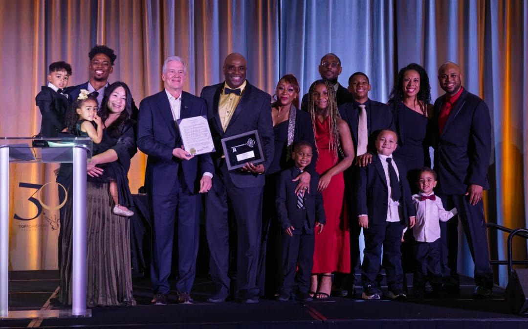 City of Plano Honors Lawrence Mann with Key to the City and Declares May 1, 2026, "Lawrence Mann Day" 3 Lawrence Mann surrounded by his family alongside Plano Mayor John Muns, holding the Key to the City and proclamation at the Top Achievers Foundation 30th Anniversary Gala.